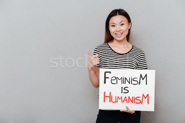 Happy woman holding blank with text about feminism. Stock photo © deandrobot