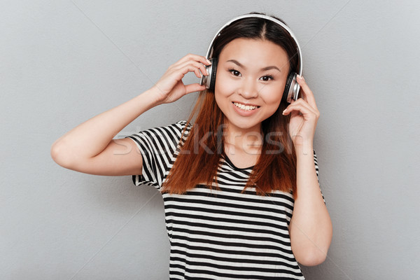 Cheerful young pretty woman listening music with headphones Stock photo © deandrobot