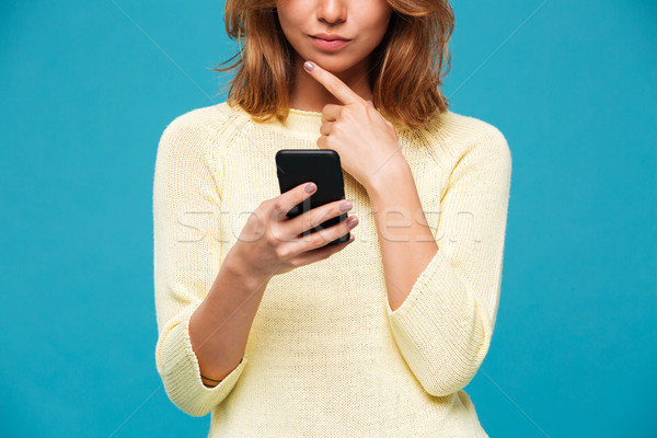 Cropped image of woman in sweater using smartphone Stock photo © deandrobot