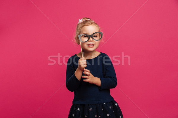 Pleased young girl using paper eyeglasses and looking at camera Stock photo © deandrobot