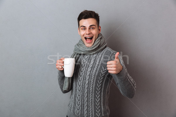 Happy man wearing warm scarf showing thumbs up. Stock photo © deandrobot