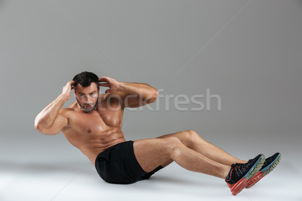 Full length portrait of a muscular strong shirtless male bodybuilder Stock photo © deandrobot
