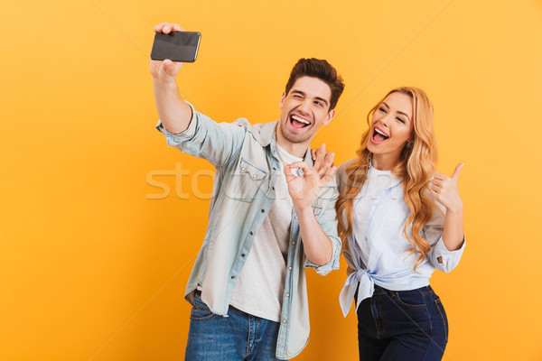 Portrait of young man and woman taking selfie photo on mobile ph Stock photo © deandrobot