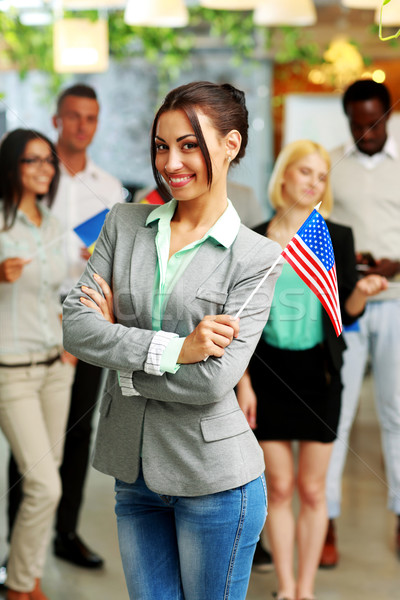 Stock photo: Smiling businesswoman holding flag of USA in front of colleagues