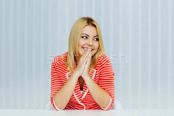 Young smiling woman sitting at the table and looking to the left at copyspace Stock photo © deandrobot