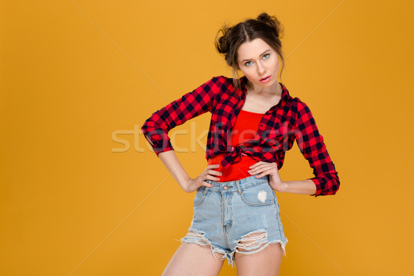 Thoughtful serious beautiful young woman standing with hands on waist  Stock photo © deandrobot
