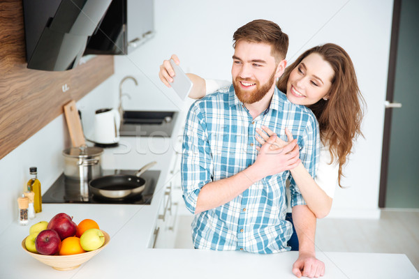 Couple making selfie photo on smartphone at the kitchen Stock photo © deandrobot