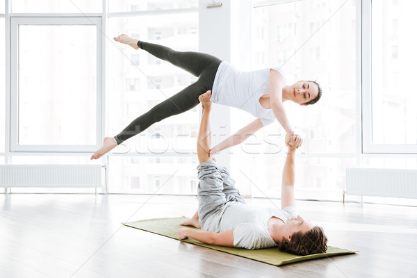 Attractive woman stretching and doing acro yoga with partner Stock photo © deandrobot