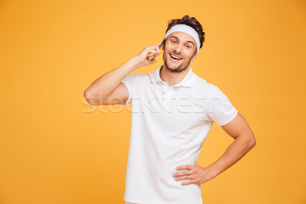 Stock photo: Happy young sportsman talking on mobile phone
