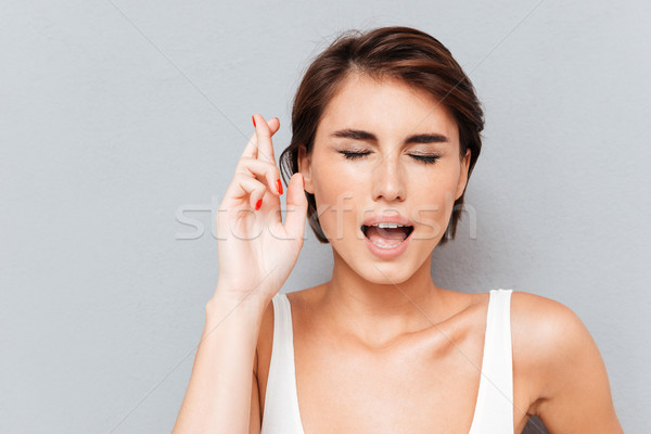 Woman with crossed fingers and closed eyes Stock photo © deandrobot