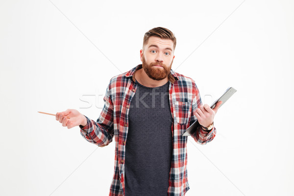 Portrait of a confused man shrugging shoulders and holding clipboard Stock photo © deandrobot