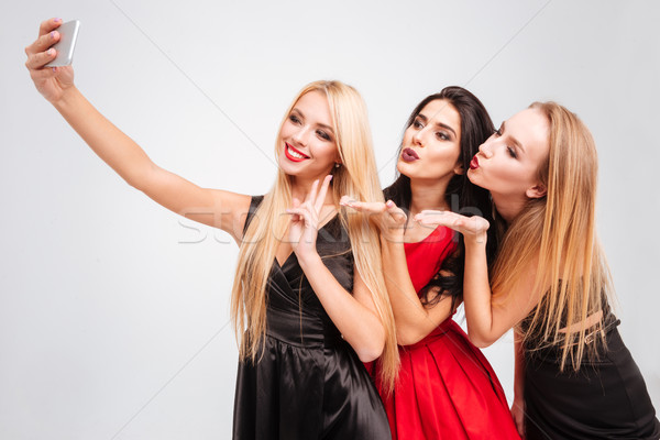 Three women sending kisses and taking selfie with mobile phone Stock photo © deandrobot