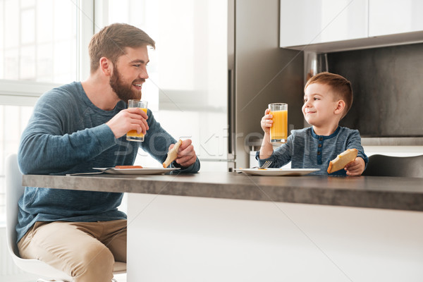 Handsome young father eating at kitchen with his little son Stock photo © deandrobot