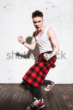 Hipster in shirt sitting near the wall Stock photo © deandrobot