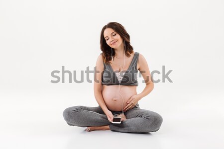 Soddisfatto donna incinta seduta piano ascolto musica Foto d'archivio © deandrobot