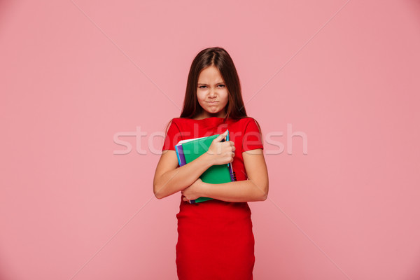 Unhappy displeased girl in red dress holding book and looking camera isolated Stock photo © deandrobot