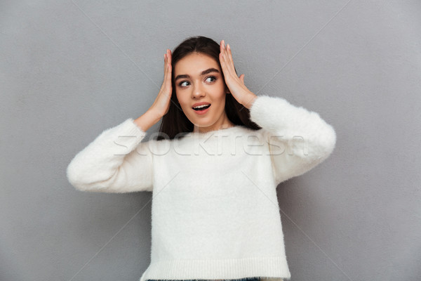 Young surprised woman in white soft sweater holding her head, lo Stock photo © deandrobot