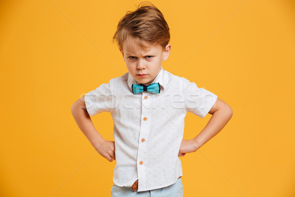 Angry little boy child standing isolated over yellow Stock photo © deandrobot