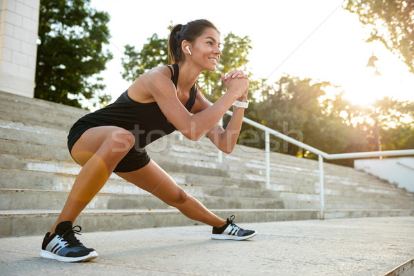 Portré mosolyog fitnessz nő fülhallgató nyújtás lépcsősor Stock fotó © deandrobot