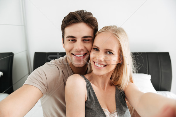 Young happy couple making selfie while lying in bed Stock photo © deandrobot