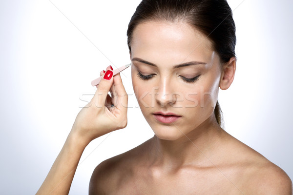 Beautiful young woman plucking eyebrows Stock photo © deandrobot
