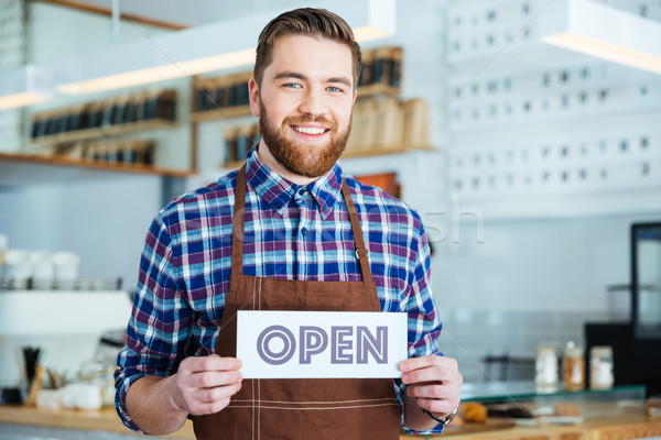 Happy attactive young barista holding open sign at coffee shop Stock photo © deandrobot