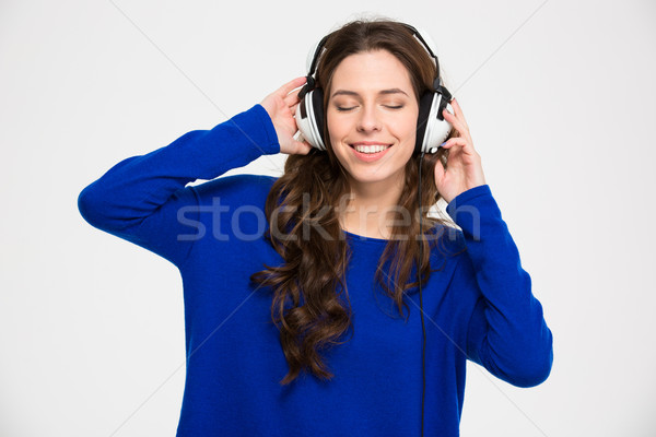 Smiling inspired young woman with closed eyes listening to music Stock photo © deandrobot