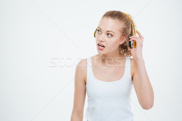 Thoughtful curious young woman taking off yellow headphones  Stock photo © deandrobot