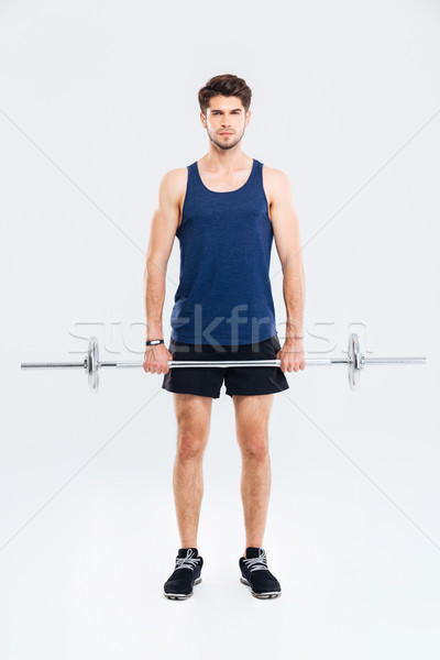 Full length of serious young sportsman exercising with barbell Stock photo © deandrobot