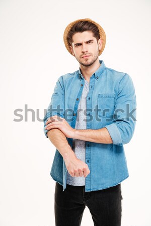 Serious handsome young man standing and rolling up his sleeves Stock photo © deandrobot