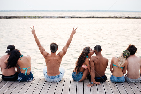 Happy couples sitting and hugging on pier near the sea Stock photo © deandrobot