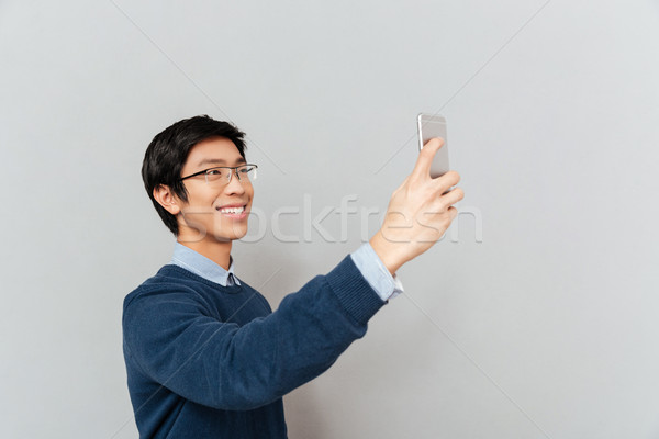 Asian man photographs on the phone Stock photo © deandrobot