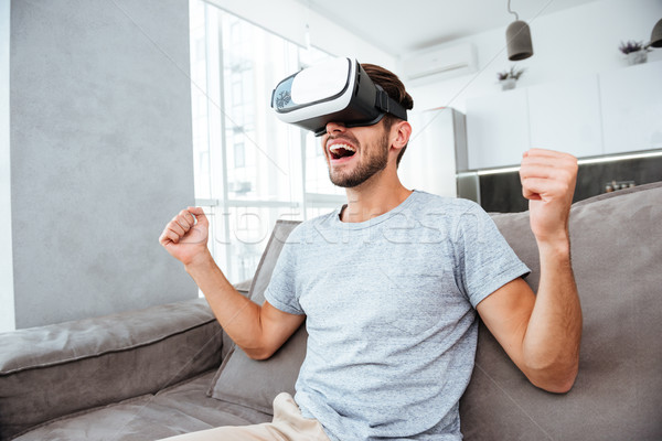 Young man making winner gesture while wearing virtual reality device Stock photo © deandrobot