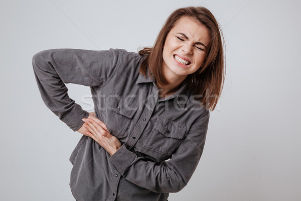 Sick young woman touching her body. Stock photo © deandrobot