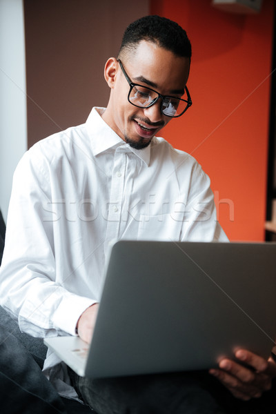 Happy african businessman wearing glasses coworking. Stock photo © deandrobot