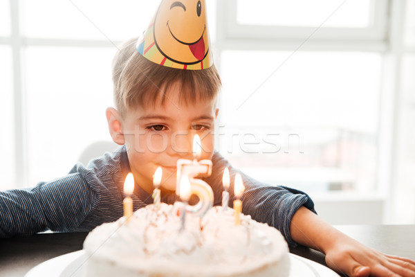 Birthday boy sitting in kitchen near cake while smiling Stock photo © deandrobot