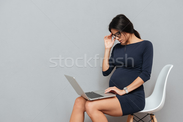 Concentrated pregnant business woman using laptop computer Stock photo © deandrobot