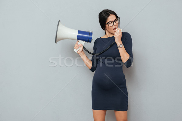 Serious pregnant business lady holding loudspeaker. Stock photo © deandrobot