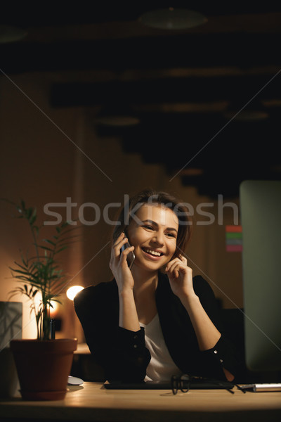 Smiling young woman designer talking by phone. Stock photo © deandrobot