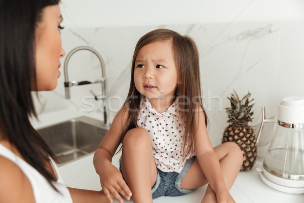 Little asian girl with frowning face looking at her mother Stock photo © deandrobot