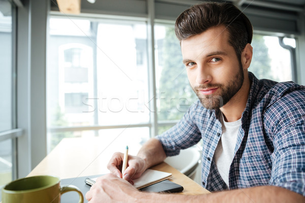 Cheerful man in office coworking while writing notes. Stock photo © deandrobot