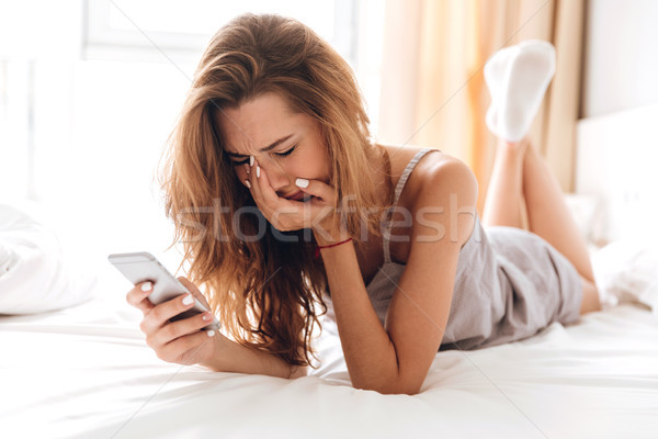 Sad emotional pretty lady lies on bed indoors. chatting Stock photo © deandrobot