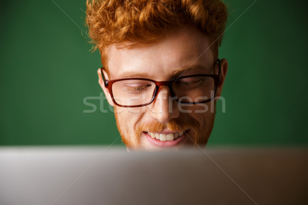 Stock photo: Cropped photo of young readhead man in glasses, working with lap