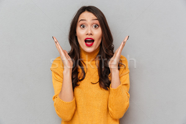 Image of Surprised brunette woman in sweater looking at camera Stock photo © deandrobot