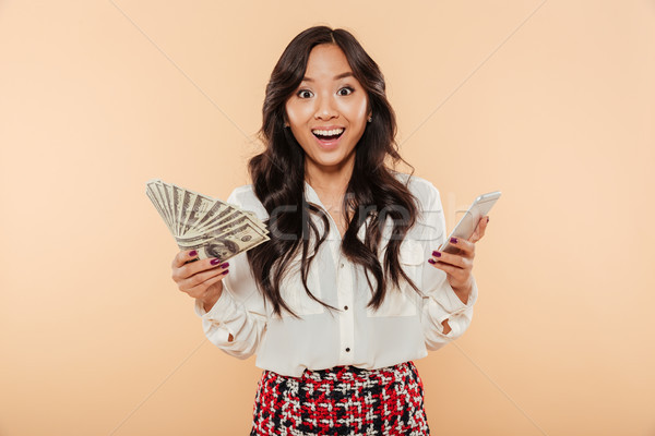 Excited lady holding fan of 100 dollar bills in one hand and tre Stock photo © deandrobot