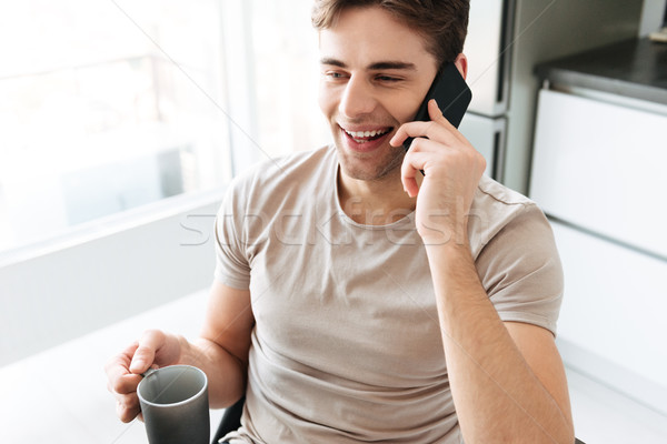 Portrait of cheerful attractive man talking on phone at home Stock photo © deandrobot
