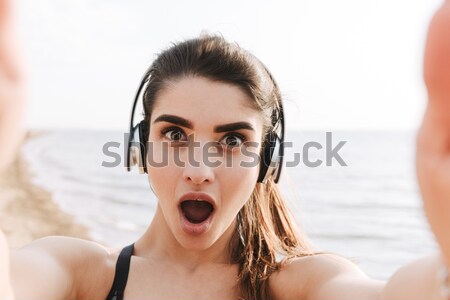 Surprised young sportswoman with headphones Stock photo © deandrobot