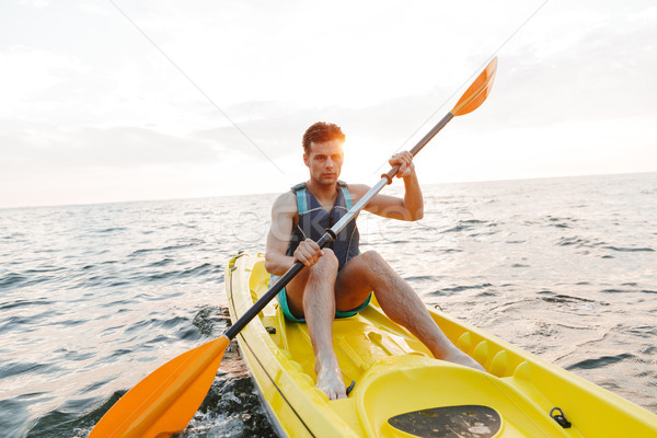 Handsome man kayaking on lake sea in boat. Stock photo © deandrobot