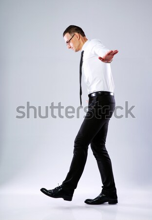 Businessman walking on invisible rope on gray background Stock photo © deandrobot