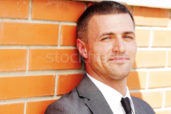 Closeup portrait of a handsome businessman against red brick wall Stock photo © deandrobot